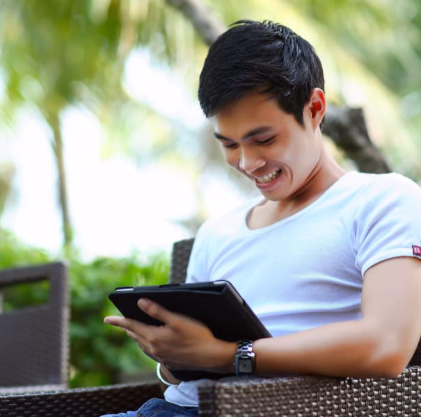 A man sitting down looking at a website on a tablet. He is having a great user experience (UX)